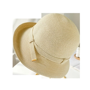 Dettaglio della trama del cappello di paglia beige con nastro e chiusura dorata