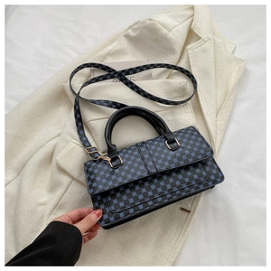 Detail of black crossbody bag with blue dot pattern and elegant gold hardware