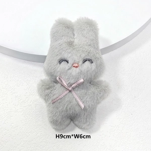 Vue détaillée du lapin en peluche gris avec nœud rose, mesurant 9cm de haut et 6cm de large