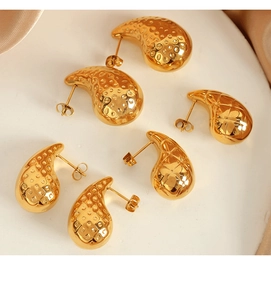 Macro view of teardrop titanium steel earrings with 18K gold plating and hammered texture