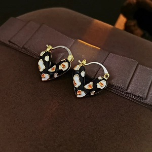 Nahaufnahme von Vintage-Herzohrringen mit Trikolore-Emaille auf einer Geschenkbox