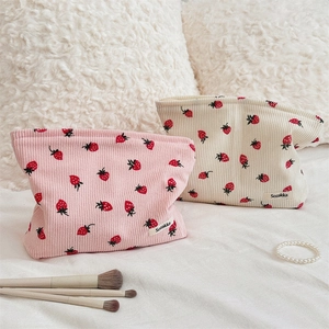 Détail du sac bandoulière en velours rose avec imprimé fraise et étiquette de marque