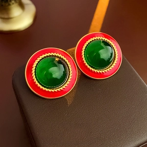 Macro detail of vintage round earrings featuring red enamel and green resin in gold finish