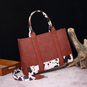 Bolso bohemio de cuero marrón con detalles y correa con estampado de vaca en blanco y negro