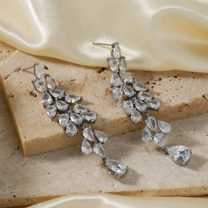 Elegant silver tassel earrings with teardrop zirconia crystals on satin fabric background