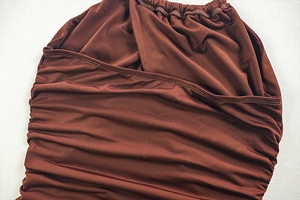 Detailed view of dark brown elastic knit fabric with crossover pleated design on the waist