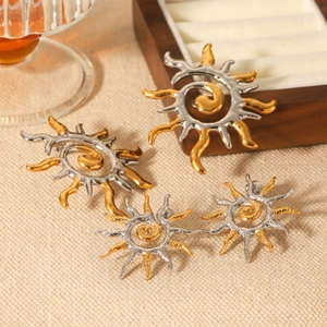 Detailed view of sunburst earrings in gold and silver tones on a wooden jewelry box