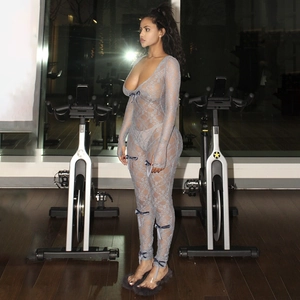 Detailed view of grey sheer lace bodysuit with blue bow accents in a gym setting