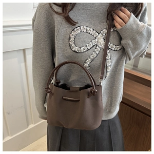 Detailed view of the dark brown bucket bag with adjustable strap and metal hardware