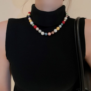 Close-up of vibrant multicolored pearl necklace on model with elegant black knitwear