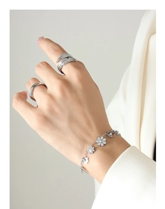 Primo piano dell'elegante bracciale a margherita e anelli a piuma su una mano femminile