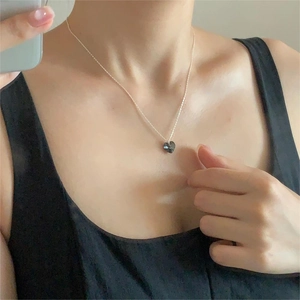 Minimalist silver heart necklace with black crystal pendant worn by a model
