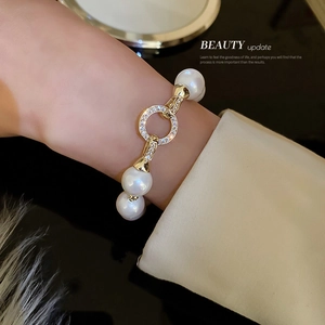 Elegant gold plated pearl bracelet with zircon encrusted ring worn by a model