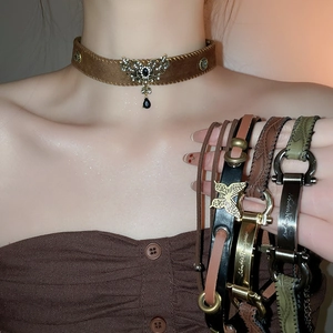 Close-up of vintage brown suede choker with butterfly pendant and leather wristbands
