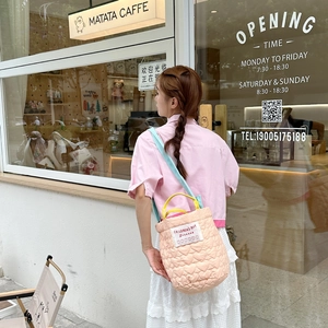 Détail du sac seau matelassé rose en forme de cœur avec poignées jaunes et bandoulière