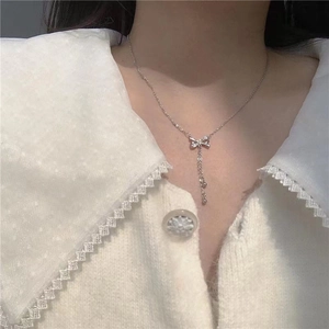 Close-up of elegant silver butterfly tassel necklace worn by a model over white lace top