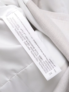 Detail shot of the garment care label showing 100% cotton material in multiple languages
