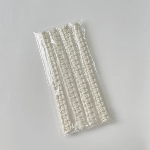 Macro detail of four white hand-woven cotton curtain tiebacks in clear plastic packaging