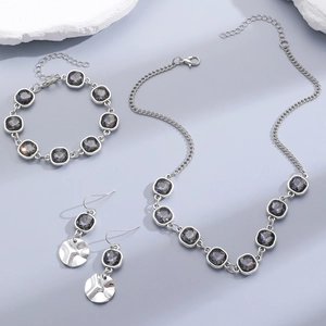 Detailed view of silver jewelry set with dark grey acrylic crystals and hammered charms