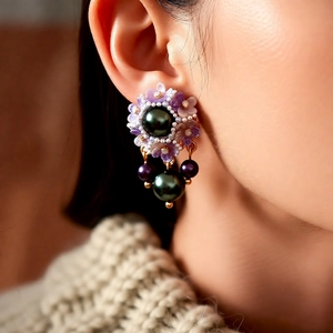 Close-up of vintage flower earrings with purple petals and green pearls on a model