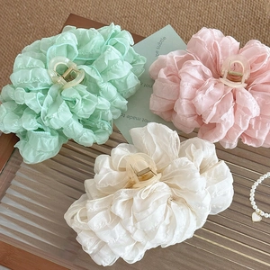 Large layered bow hair claw clips in pastel green, pink, and cream with ruffle fabric texture