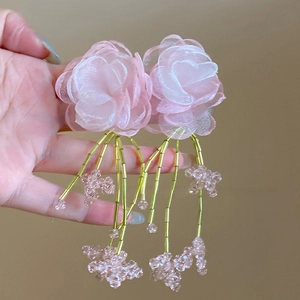 Macro shot of pink floral tassel earrings with gold beads and delicate sheer fabric petals