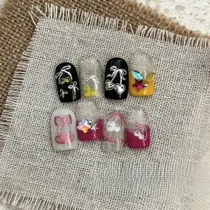 Close-up of cherry nail art stickers featuring metallic bows and gemstone embellishments
