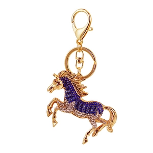 Golden horse keychain with blue and clear rhinestones on a white background