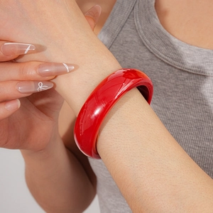 Gros plan d'un bracelet jonc épais en résine rouge brillant sur un modèle féminin