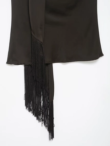 Detailed close-up of long black tassels on a smooth satin finish fashion top