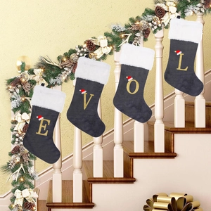 Detailed view of four grey plush Christmas stockings with gold embroidered letters on stairs