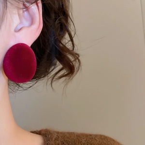 Gros plan d'un mannequin portant de grandes boucles d'oreilles ovales en velours rouge