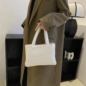 Fashionable white plush handbag for women shown by a model in a modern room setting