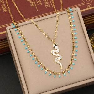 Detailed close-up of a gold double-layer necklace with a crystal snake pendant and turquoise beads