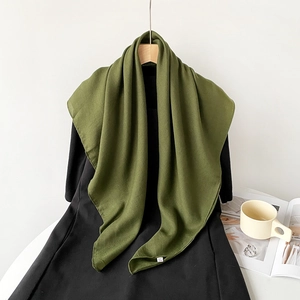 Detail shot of an olive green linen scarf fabric texture with a small woven brand label