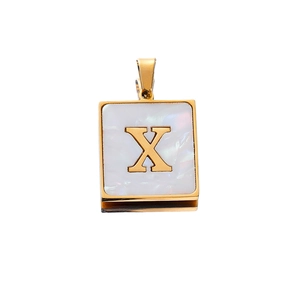 Macro detail of square stainless steel gold pendant with white shell inlay and letter X