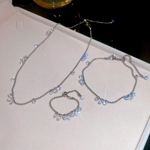 Macro shot of silver stainless steel jewelry set with sparkling zircons on pink tray
