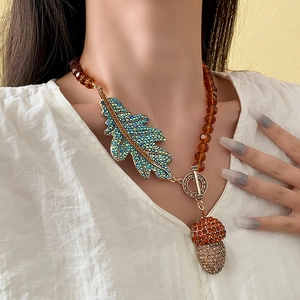 Detailed view of vintage crystal leaf and acorn charms on an amber beaded necklace
