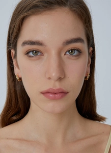 Close-up of gold star earrings with cubic zirconia worn by a model in a natural setting