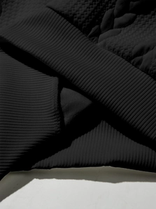 Detailed macro view of black waffle knit fabric with ribbed cuffs on heavy weight sweatshirt