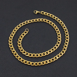 Macro view of coiled gold vacuum-plated stainless steel Cuban link chain over black texture