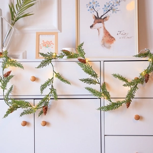 Guirlande de Noël avec aiguilles de pin, lumières LED chaudes et pommes de pin sur meuble