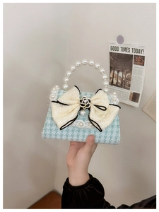 Detail of light blue houndstooth handbag with pearl handle and camellia bow decoration