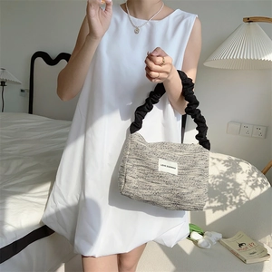 Detail of grey textured tweed tote bag featuring black ruched cloud-style handle