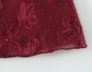 Detail of wine red mesh lace with delicate floral embroidery and shimmering sequins