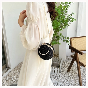 Detail of a round black rhinestone evening bag with golden ring handle and chain strap