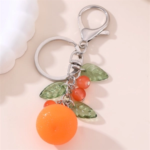 Close-up of cute fruit keychain featuring orange charm and green leaves on silver ring