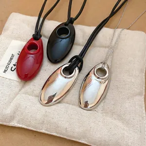 Minimalist geometric oval pendant necklaces in red, black, and silver on cotton pouch