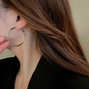 Close-up of a model wearing large silver-toned round hoop earrings in a minimalist style