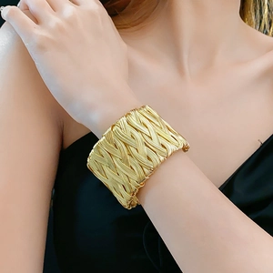 Close-up of a wide vintage-style braided gold cuff bracelet worn on a female wrist